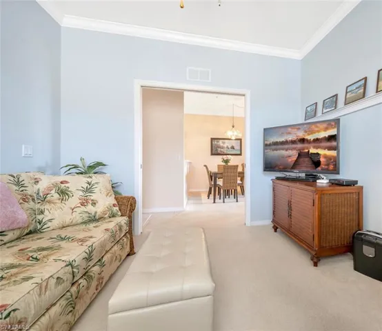 Living area featuring visible vents, crown molding, light carpet, and baseboards