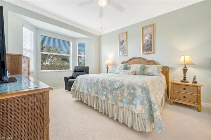 Bedroom featuring baseboards, ceiling fan, crown molding, and light colored carpet