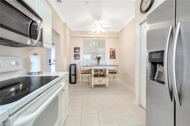 Kitchen with light tile patterned floors, stainless steel appliances, ornamental molding, and white cabinets
