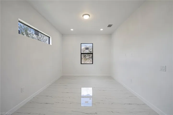 Unfurnished room with healthy amount of natural light, light marble finish flooring, and recessed lighting
