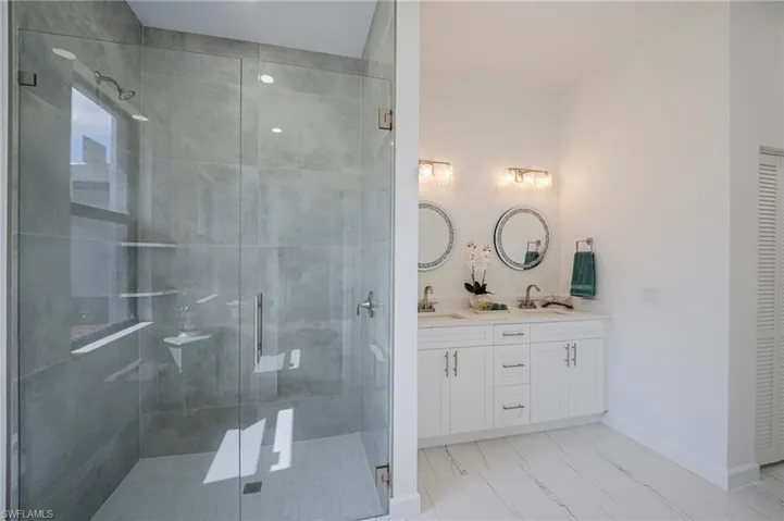 Full bath with double vanity, a shower stall, and a closet
