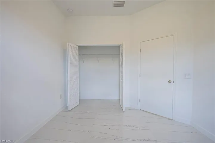 Unfurnished bedroom featuring light marble finish flooring and a closet