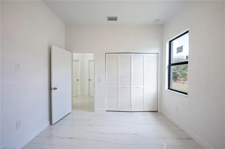 Unfurnished bedroom with light marble finish floors and a closet