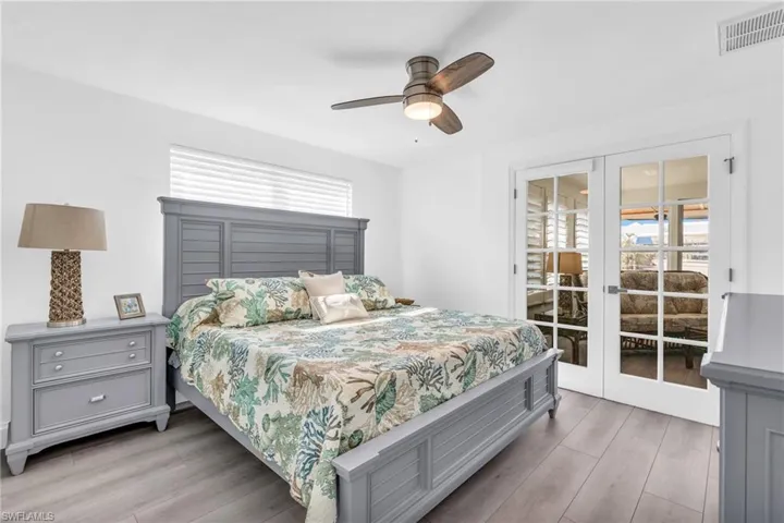 Bedroom featuring multiple windows, access to exterior, light hardwood / wood-style floors, and french doors - VIRTUALLY ENHANCED