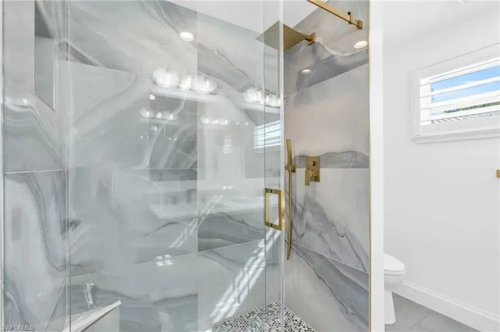 Bathroom featuring gold accents and custom cabintery with double shower head - VIRTUALLY ENHANCED