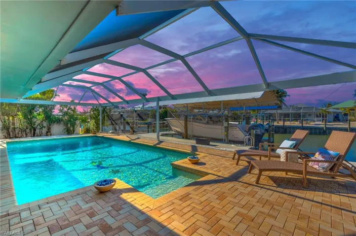 Pool at dusk featuring panoramic screen enclosure and a covered patio area - VIRTUALLY ENHANCED
