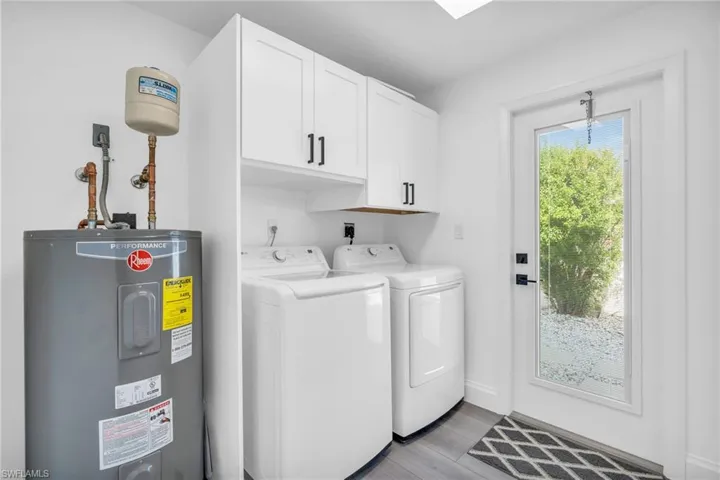 Laundry room featuring cabinets, electric water heater, independent washer and dryer with exterior access - VIRTUALLY ENHANCED