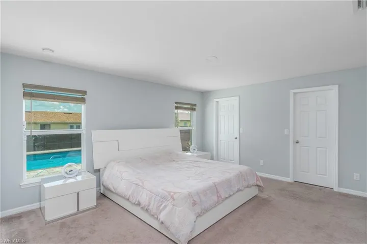 Bedroom with light carpet and multiple windows