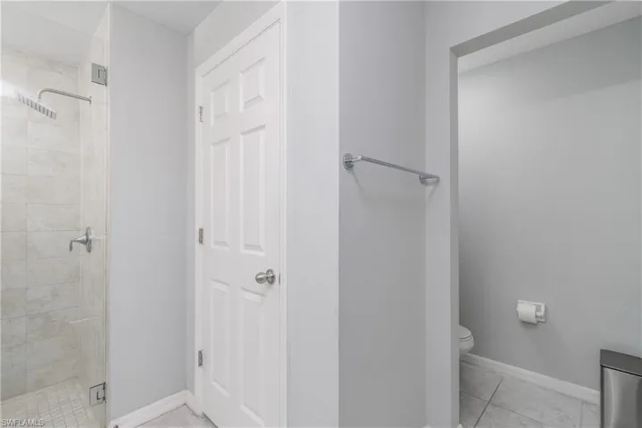 Bathroom featuring tile flooring, tiled shower, and toilet