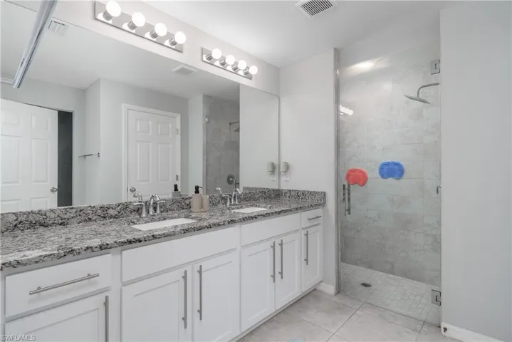 Bathroom featuring tiled shower, tile floors, double sink, and oversized vanity