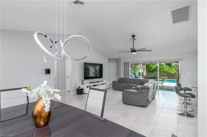 Dining room featuring ceiling fan, light tile flooring, and lofted ceiling
