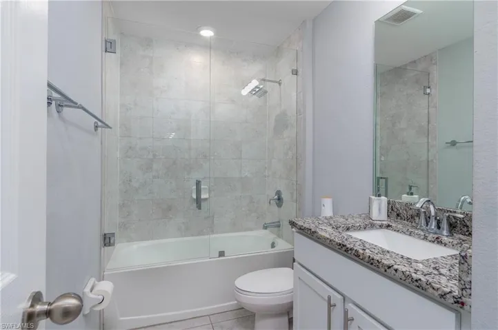 Full bathroom with combined bath / shower with glass door, vanity, toilet, and tile floors