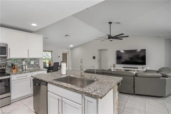 Kitchen featuring white cabinetry, appliances with stainless steel finishes, an island with sink, sink, and ceiling fan