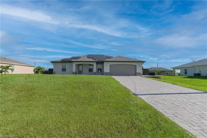 View of front of house featuring a garage, a front yard, and solar panels