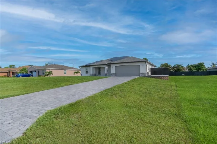 Ranch-style house with a garage and a front lawn