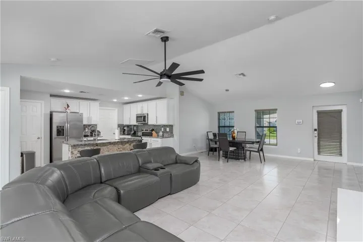 Living room with sink, lofted ceiling, light tile flooring, and ceiling fan