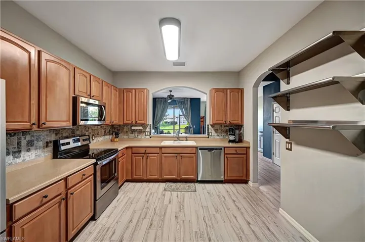 Kitchen with sink, light hardwood / wood-style flooring, ceiling fan, appliances with stainless steel finishes, and tasteful backsplash