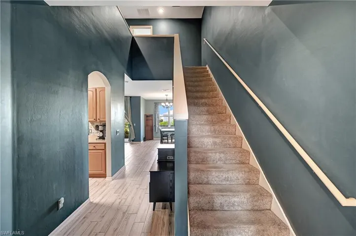 Stairs with hardwood / wood-style floors, a notable chandelier, and a high ceiling