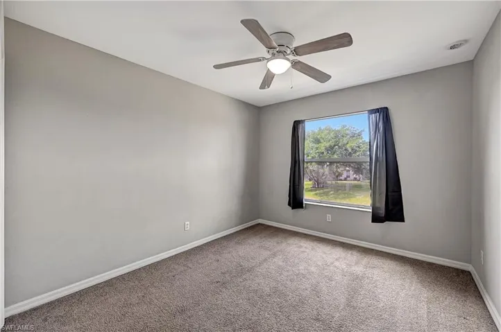 Carpeted empty room featuring ceiling fan
