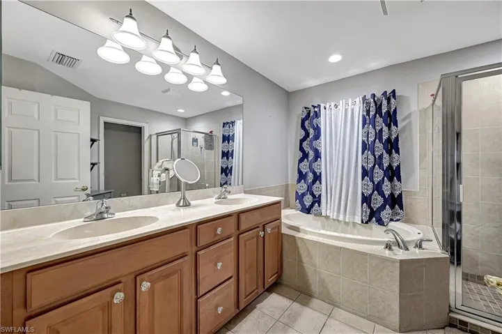 Bathroom with vanity, tile patterned flooring, and plus walk in shower