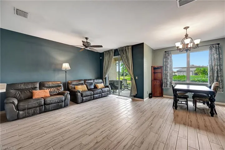 Living room featuring plenty of natural light, ceiling fan with notable chandelier, and light hardwood / wood-style flooring