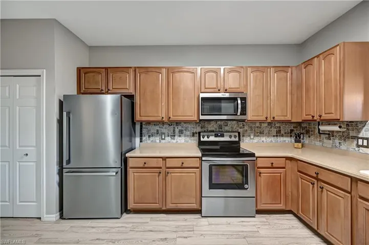 Kitchen featuring decorative backsplash, appliances with stainless steel finishes, and light wood-type flooring