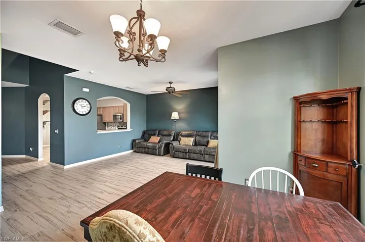 Dining area featuring ceiling fan with notable chandelier and light wood-type flooring