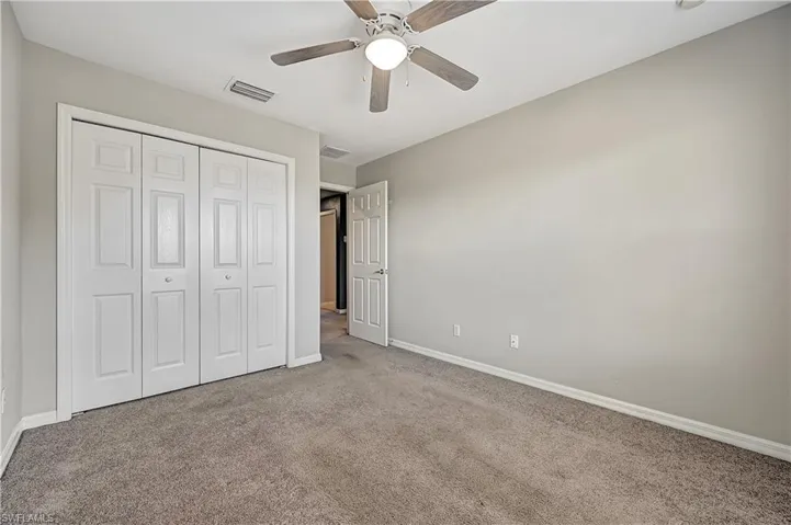 Unfurnished bedroom with a closet, ceiling fan, and light colored carpet