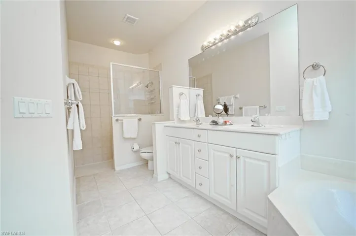Full bathroom featuring tile patterned floors, vanity, toilet, and independent shower and bath