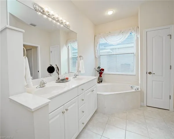 Bathroom with tile patterned flooring, vanity, and a tub
