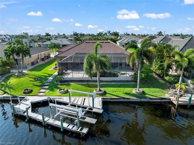 View of dock featuring a lawn, glass enclosure, and a water view