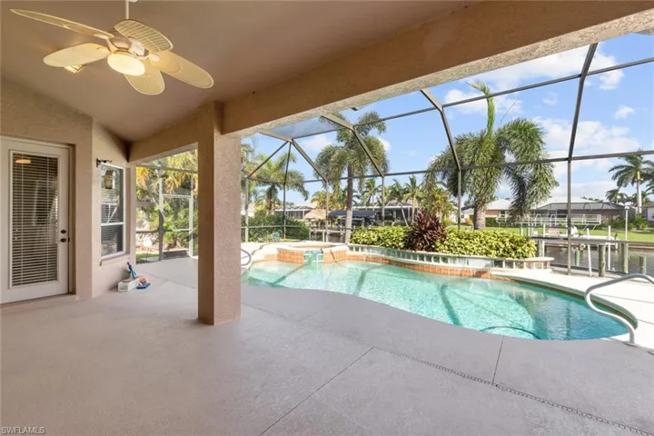 View of swimming pool with ceiling fan, a patio, an in ground hot tub, and a lanai