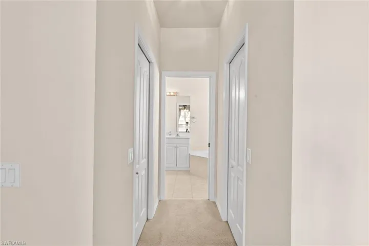 Hali into the master bath with his and hers closets with light carpet