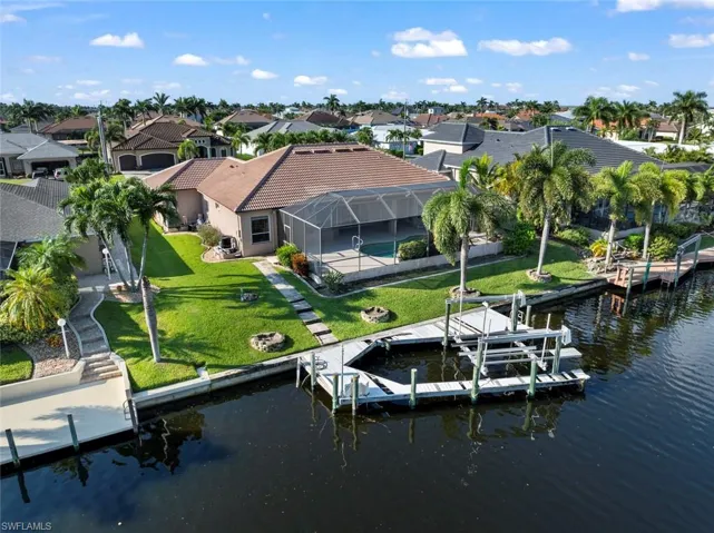 View of dock featuring a lanai, a water view, a patio area, and a lawn