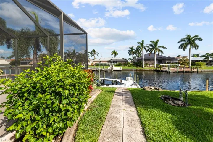 Dock area with a lanai, a water view, and a lawn