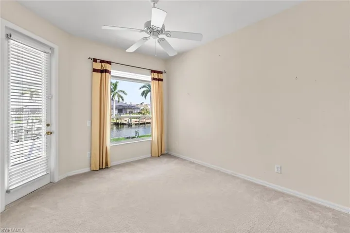 Spare room with light carpet, a water view, and ceiling fan