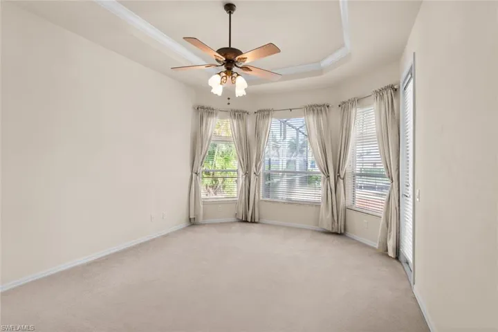 master bedroom  featuring light carpet, a raised ceiling, crown molding, and ceiling fan
