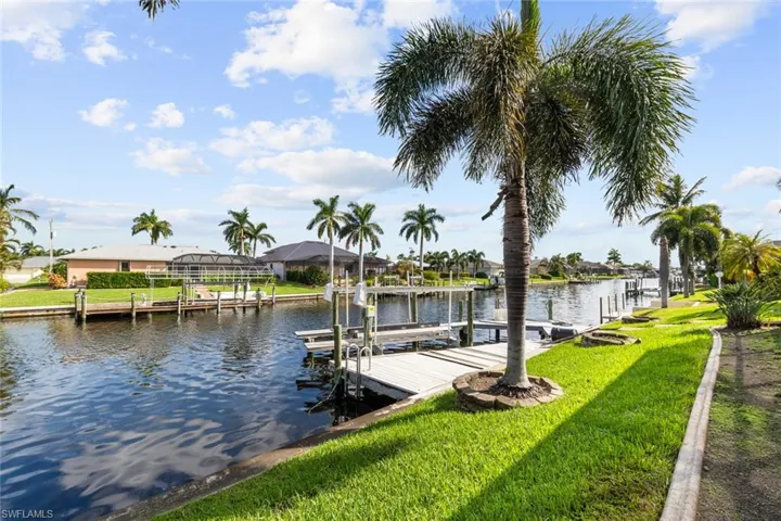 Dock area with a yard, a water view, and glass enclosure
