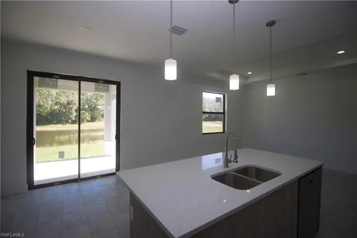 Kitchen featuring pendant lighting, plenty of natural light, a center island with sink