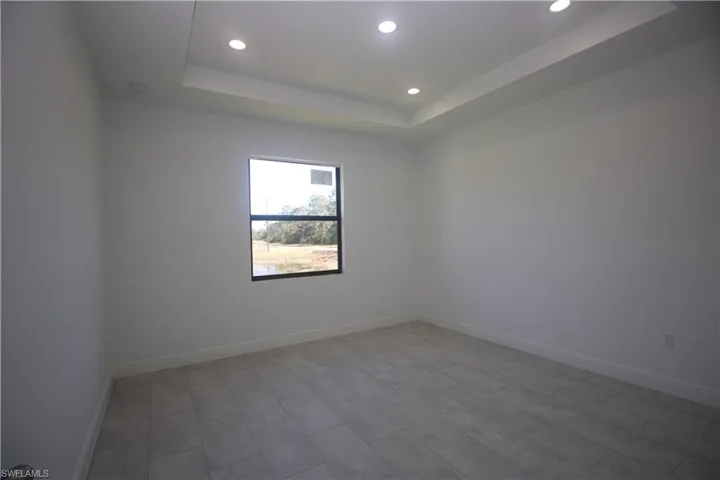 Master bedroom with a raised ceiling and light tile / wood-style flooring