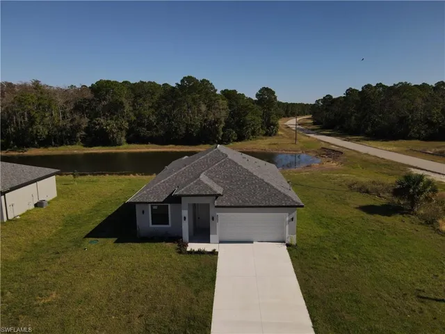 View of front of property featuring a front yard, a two car garage, and a water view