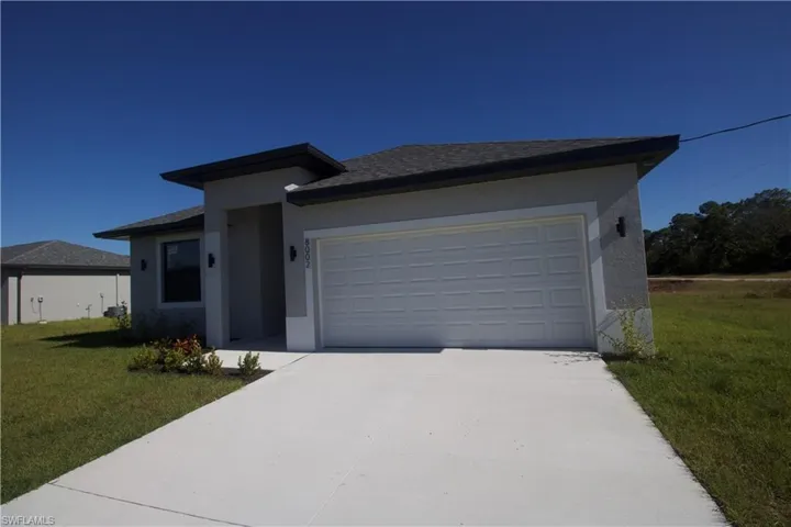 View of front of property with a two car garage and a front lawn