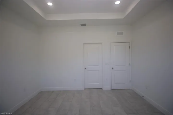 Master bedroom with a raised ceiling and light tile / wood-style flooring