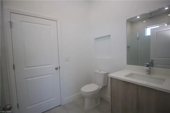 Jack & Jill style Bathroom with a tile shower, tile patterned floors, vanity, and toilet