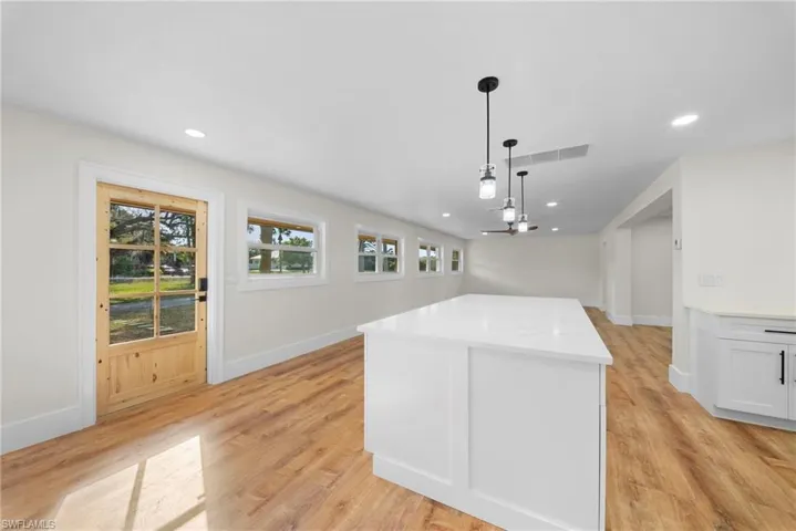 Kitchen featuring a kitchen island, light wood-type flooring, open floor plan, and light stone countertops