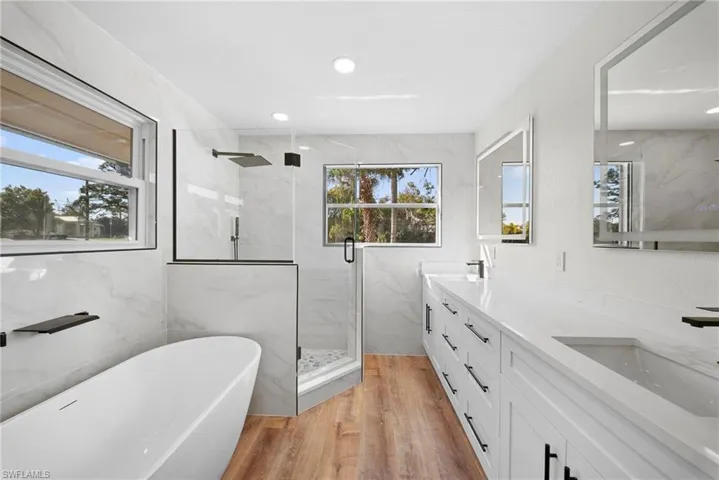Full bathroom with a marble finish shower, double vanity, plenty of natural light, a soaking tub, and recessed lighting
