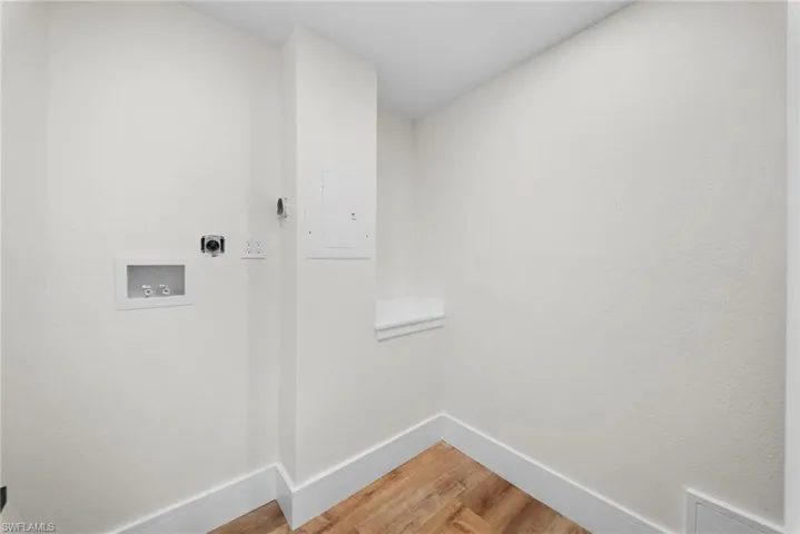 Laundry room with light wood finished floors, electric panel, hookup for a washing machine, and hookup for an electric dryer