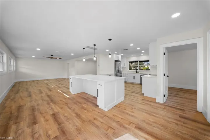 Kitchen featuring open floor plan, light wood-style flooring, white cabinetry, and a spacious island