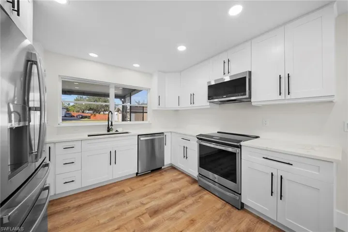 Kitchen featuring stainless steel appliances, white cabinets, light wood-style flooring, and recessed lighting