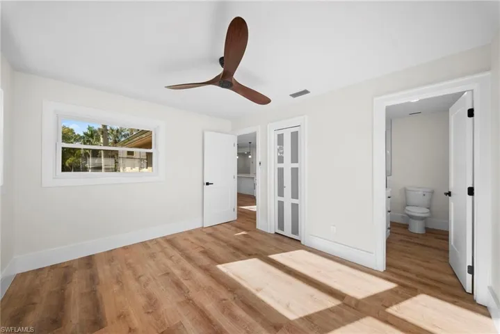 Unfurnished bedroom featuring light wood-style floors, ceiling fan, and ensuite bathroom